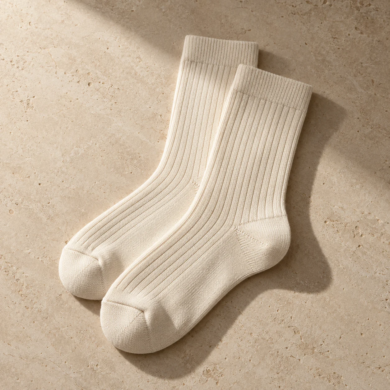 Ecru ribbed crew sock concept on a warm stone background